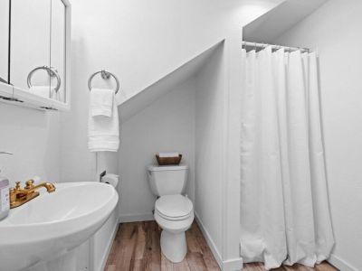 The immaculate white walls, glistening fixtures, and spotless surfaces create a fresh and inviting atmosphere. Providing a serene space for personal care and relaxation.