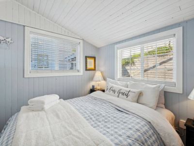Main floor bedroom hosts a plush, queen-sized bed nestled in this cozy room. Sink into the luxurious bedding and fall asleep to the sound of the rhythm of the water.
