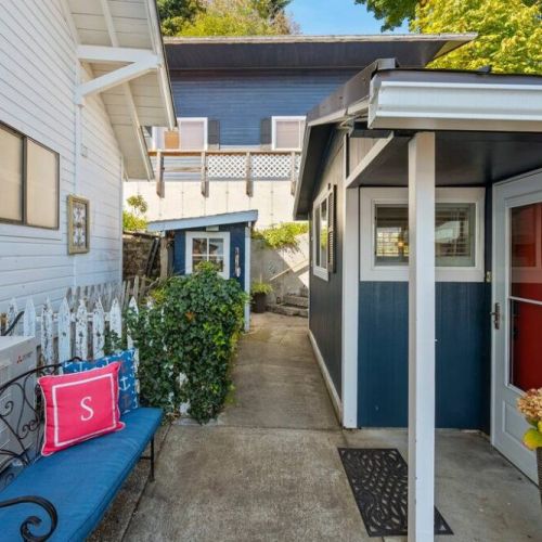 The view of the entrance walkway.  Parking is available in front of the garage (large blue building in background). Stairs lead down to the beach house.