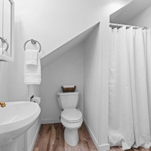 The immaculate white walls, glistening fixtures, and spotless surfaces create a fresh and inviting atmosphere. Providing a serene space for personal care and relaxation.