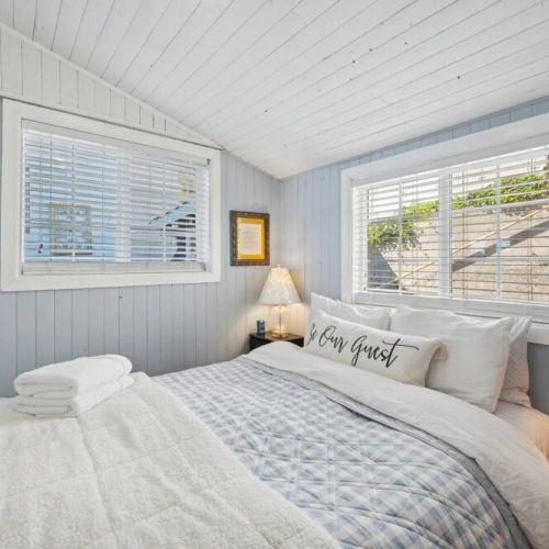 Main floor bedroom hosts a plush, queen-sized bed nestled in this cozy room. Sink into the luxurious bedding and fall asleep to the sound of the rhythm of the water.