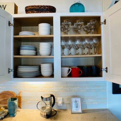 A generous collection of extra cups, glasses, and plates neatly arranged.