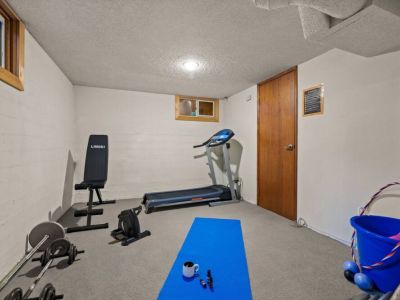 Achieve your fitness goals in the convenience of your home with this well-equipped lower-level gym area, featuring a treadmill, weight bench, and a set of dumbbells.