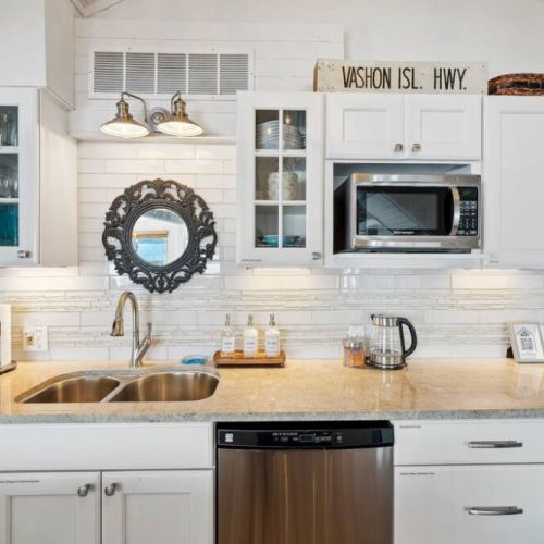 The kitchen cabinets adorned in a crisp, glossy white finish, spans the walls in a seamless, offering ample storage while maintaining a clean, uncluttered look.
