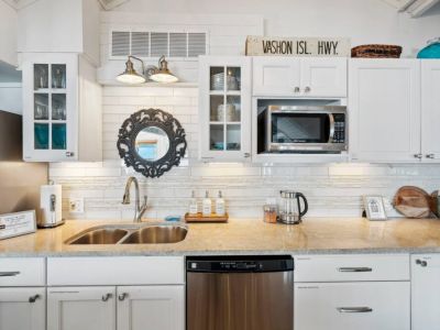 The kitchen cabinets adorned in a crisp, glossy white finish, spans the walls in a seamless, offering ample storage while maintaining a clean, uncluttered look.