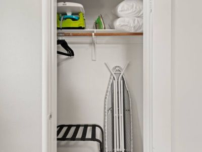 The  queen bedroom closet has a Graco Pack n Play, fitted Graco sheet, child booster/high chair, iron, ironing board, and a luggage rack.