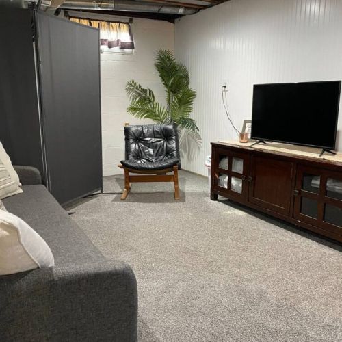 The TV console includes extra pillows and sheets for additional sleeping options.