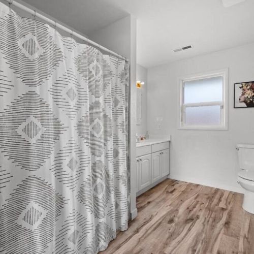 A spacious full bathroom on the main floor has sleek fixtures and modern design create a sophisticated and inviting atmosphere.