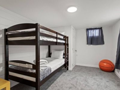 Discover the perfect kids' retreat in our twin bunkbed room. A cozy sleeping arrangement, the room is adorned with an array of kids' toys.