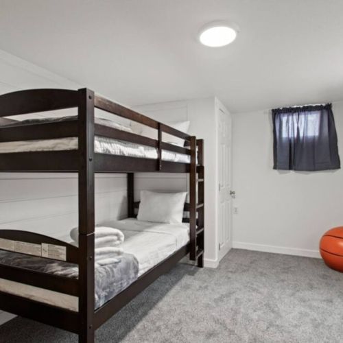 Discover the perfect kids' retreat in our twin bunkbed room. A cozy sleeping arrangement, the room is adorned with an array of kids' toys.