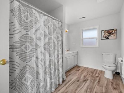 A spacious full bathroom on the main floor has sleek fixtures and modern design create a sophisticated and inviting atmosphere.