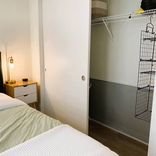The full closet includes extra pillows, a hamper, and a wire hanging shelf.