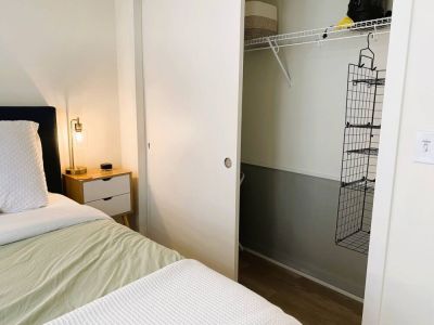 The full closet includes extra pillows, a hamper, and a wire hanging shelf.