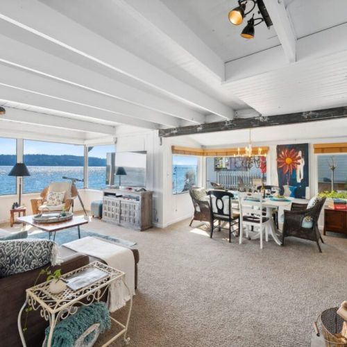 Oversized windows span the entire length of one wall, providing an unobstructed view of the majestic ocean and allowing the warm, natural light to bathe the room in a soft, welcoming glow.